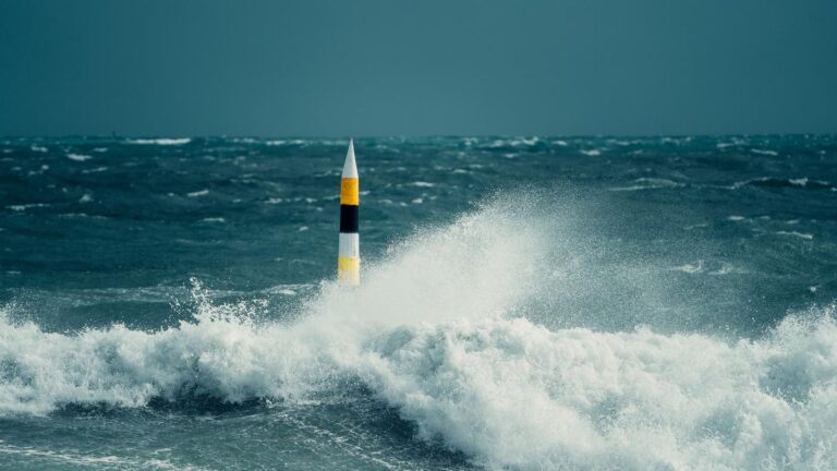 A once in a decade storm hitting the iconic Cottesloe bollard. Huge waves crash against the bollard with heavy rain pouring down.