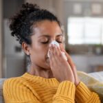 Cold sick african woman blowing nose