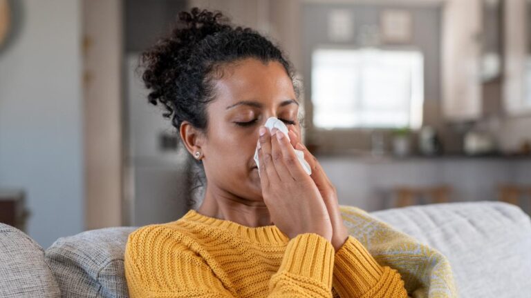 Cold sick african woman blowing nose