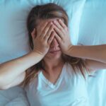 Young stressed woman lying on bed late at night suffering from i