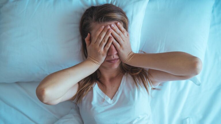 Young stressed woman lying on bed late at night suffering from i