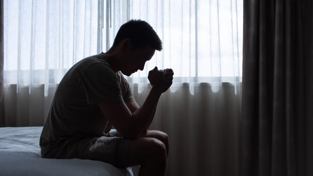 thoughtful man in a dark room with head down, Portrait of thoughtful sad man alone. prayer,  Fear, sadness, abuse, depression, addiction.