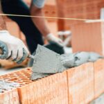 Professional worker using pan knife for building brick walls wit