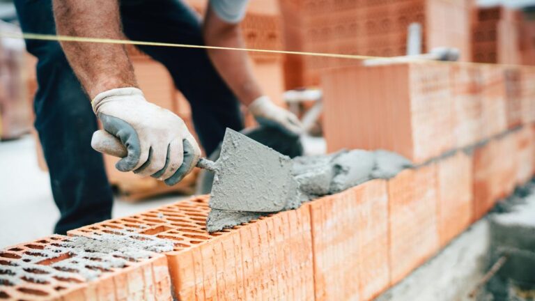Professional worker using pan knife for building brick walls wit