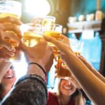 Group of happy friends drinking and toasting beer at brewery bar