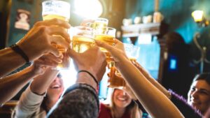 Group of happy friends drinking and toasting beer at brewery bar
