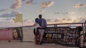 Surrounded by banners about hostages held by Hamas, a couple enjoys sunset over the Mediterranean Sea in Tel Aviv, Israel, Oct. 12, 2025. (Amit Elkayam/The New York Times)