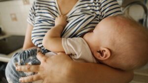 Mother's carrying toddler and breastfeeding at home