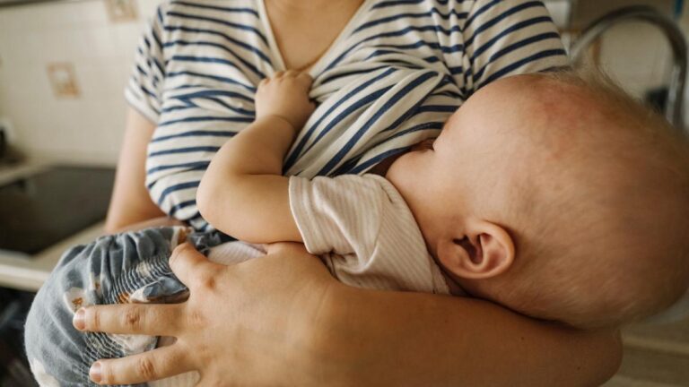Mother's carrying toddler and breastfeeding at home