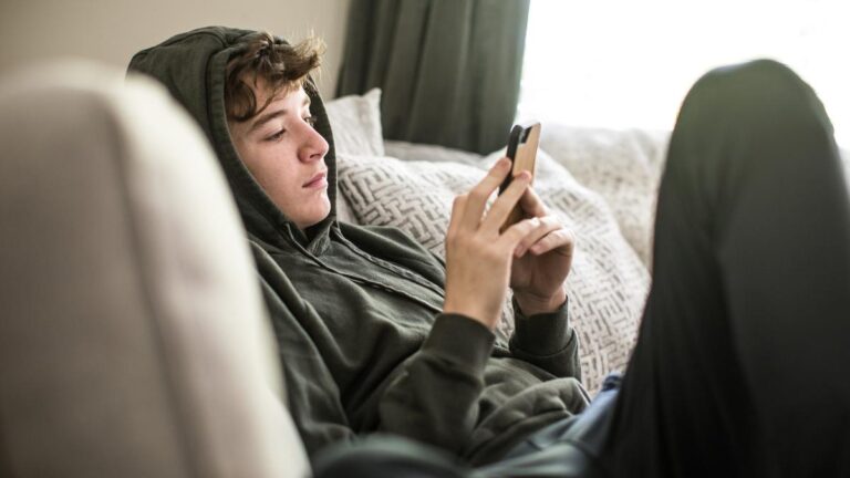 Teenage boy using smartphone at home