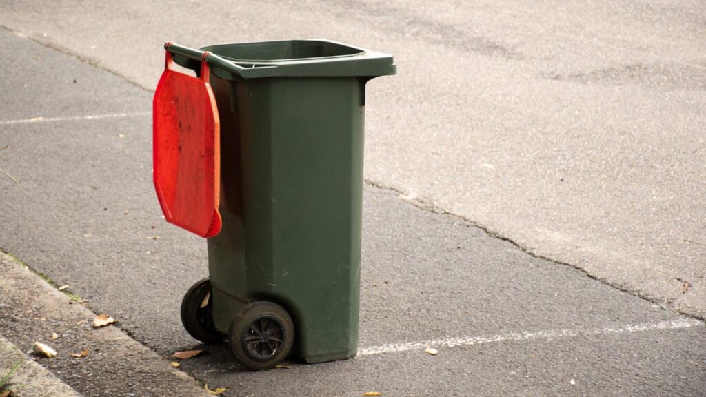 Australian garbage wheelie bin with red lid for general household on the street kerbside after council rubbish collection.