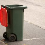 Australian garbage wheelie bin with red lid for general household on the street kerbside after council rubbish collection.