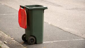 Australian garbage wheelie bin with red lid for general household on the street kerbside after council rubbish collection.