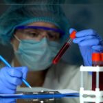 Doctor checking tube with blood analysis and making notes, lymph