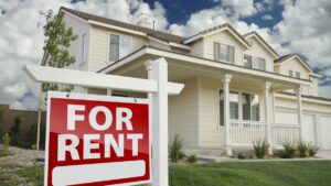 Right Facing Red For Rent Real Estate Sign in Front of Beautiful House.